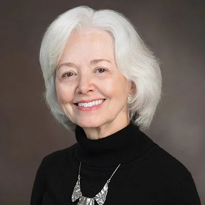 A woman with white hair wearing a black sweater.