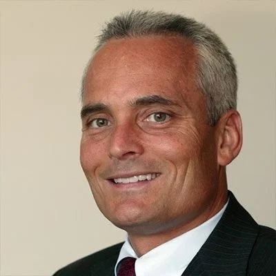 A man in suit and tie smiling for the camera.